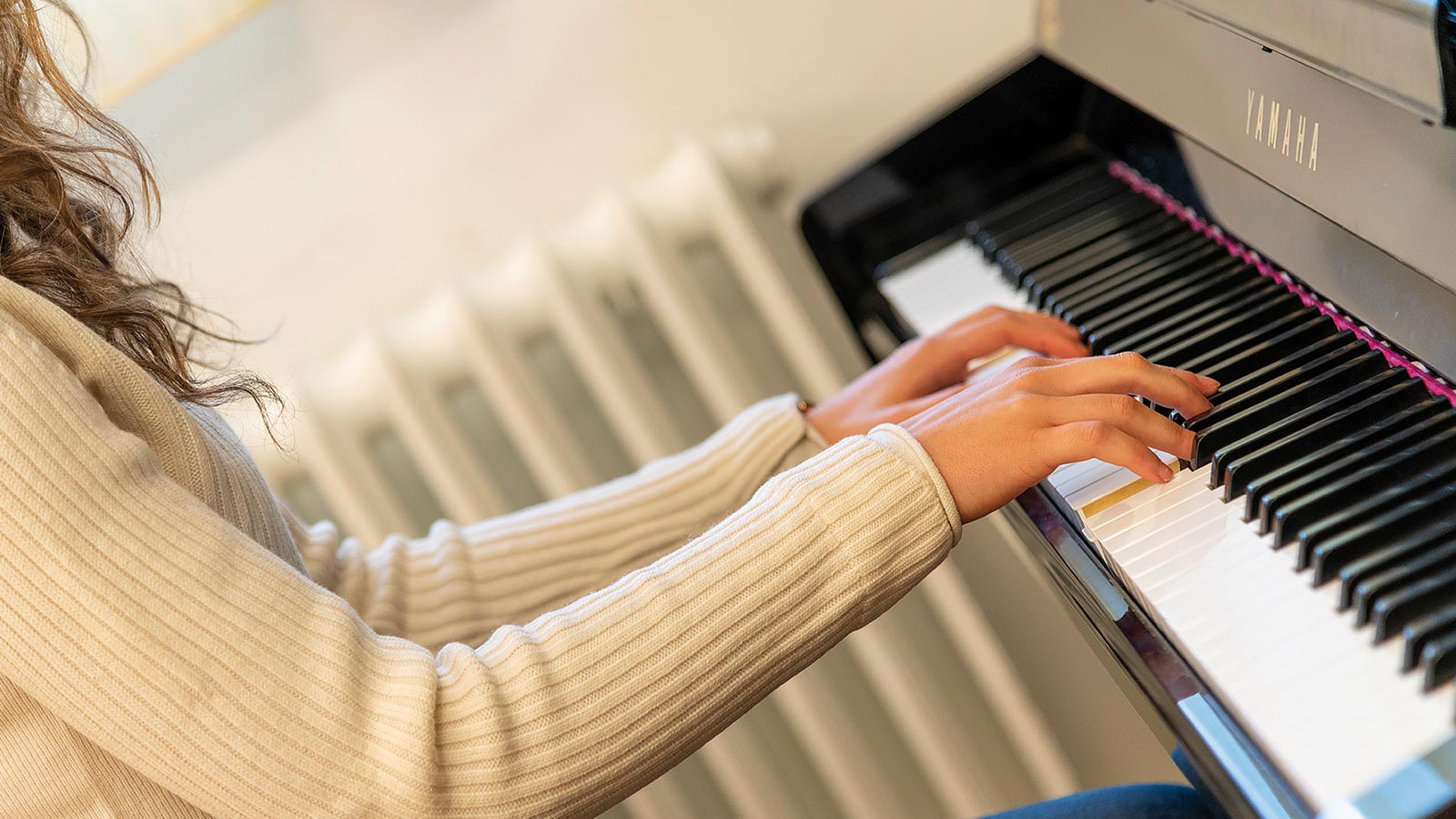 Dettaglio delle mani di una studentessa mentre si esercita al pianoforte